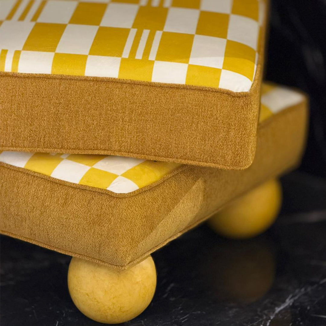 Yellow and white checkered cushion on a brown ottoman with a dark background